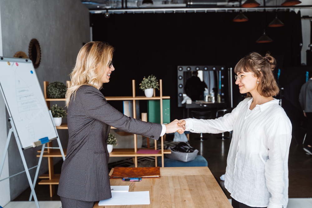 Une poignée de main entre un galeriste et un conseiller en financement dans une galerie d'art, symbolisant un partenariat stratégique au service des collectionneurs d'entreprise.