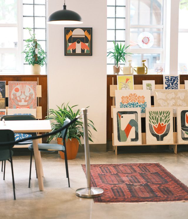 Un Art Advisor ou consultant en art, en tenue professionnelle, discute avec un client ou examine des documents dans un bureau élégant. Une œuvre d'art moderne ou un tableau est visible sur le mur derrière eux, symbolisant le conseil pour une collection d'entreprise.